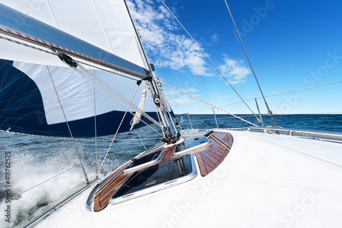 White sailing boat and bright blue sea and sky with water spraying photo
