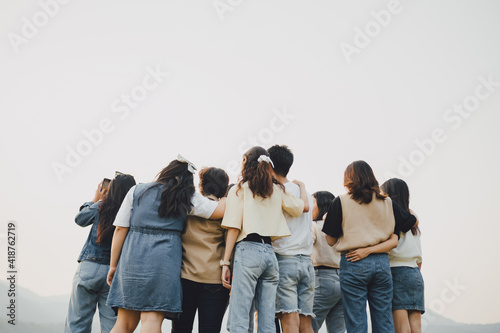 Picture from behind view of groups of friends embrace each other together. Concept for kindness support of people having fun with diversity millenials of gen z. photo