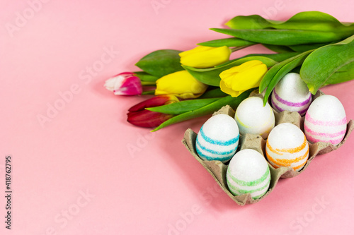 Easter painted eggs with tulips on a pink background. Copy space. Easter celebration concept