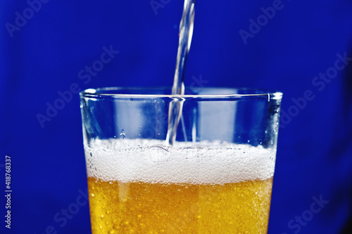Wallpaper Mural jet beer into a glass of foam bubbles close-up on a blue background Torontodigital.ca