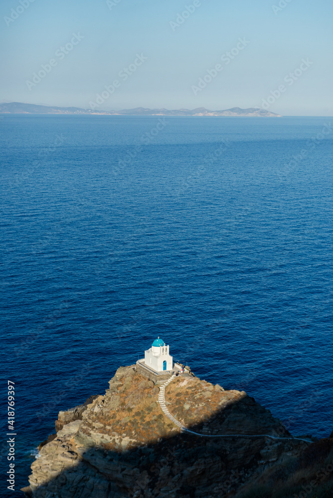 View from the top of the cliff to the Church of seven Martyrs and the aegean sea. Sifnos, Cyclades, Greece.