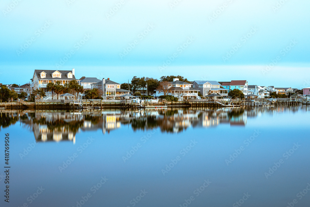 Houses on the west side of Lumina Ave reflecting in the water of the Banks Channel.