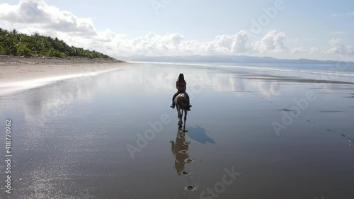Woman riding a horse alone on a beach in Costa Rica pacific ocean 