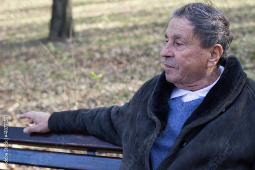 Portrait of happy senior man smiling, in the public park, outdoors. Old man relaxing outdoors and looking away. Portrait of elderly man enjoying retirement