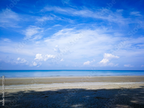 The bright blue sky and the bright white clouds, the beach and the clear blue sea in the daytime
