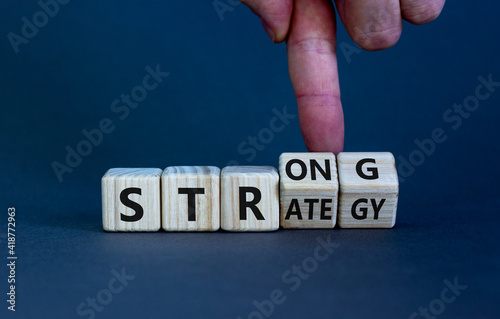 Strong strategy symbol. Businessman turns wooden cubes with words 'strong strategy'. Beautiful grey background, copy space. Business and strong strategy concept. photo