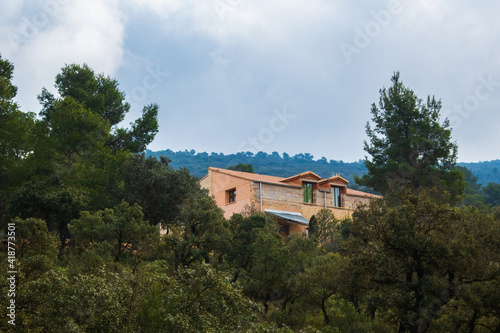Country house, in the middle of a Mediterranean forest, with a cloudy sky. 