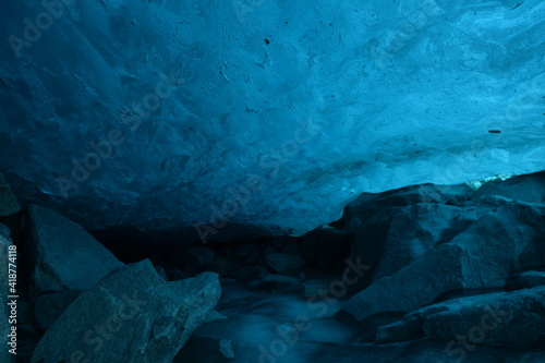 Glacier grotto with blue clear glacier ice and stones