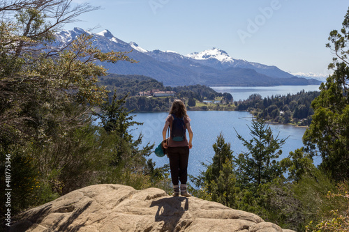 Mujer con mochila observa un paisaje de lagos y montañas photo
