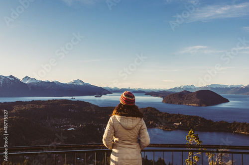 Mujer con ropa de invierno observado un paisaje de lagos y montañas