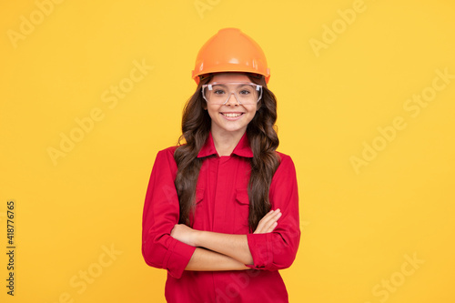 cheerful child girl in protective hard hat crossed hands, childhood development © Olena