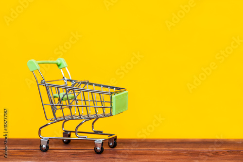 Shopping trolley on an yellow background. Shopping concept. Copy space for advertisement