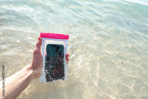 Waterproof case on a smartphone, phone for taking pictures under water. Phone in the waterproof case underwater, on the sands