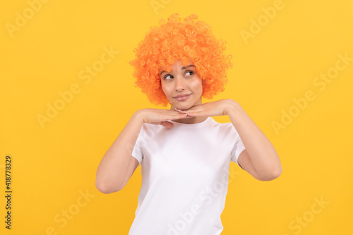 cute funny girl with fancy look wearing orange hair wig on yellow background, party