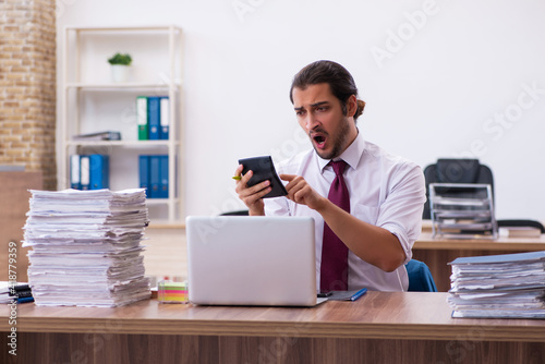 Young male bookkeeper unhappy with excessive work in the office