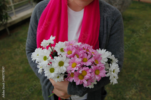Girl in pink scarf and white mask with daisies outdoors. Cancer awareness concept. 