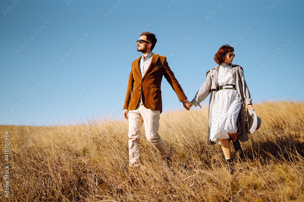 Stylish and loving couple enjoying each other outdoors. Young couple walking and hugging. Springtime.