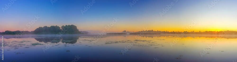 Panorama with beautiful foggy sunrise over forest lake