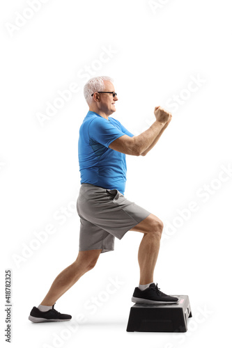 Fototapeta Naklejka Na Ścianę i Meble -  Mature man exercising on a step aerobic platform
