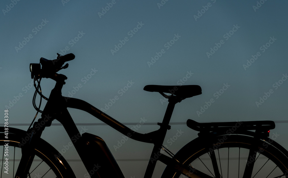 Black and gray electric bicycle in sunrise morning time on frosty field Black and gray electric bicycle in sunrise morning time on frosty field