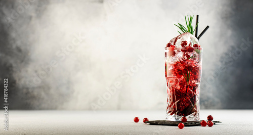Foto Cranberry cocktail with ice, rosemary and berries in highball glass, gray backgr