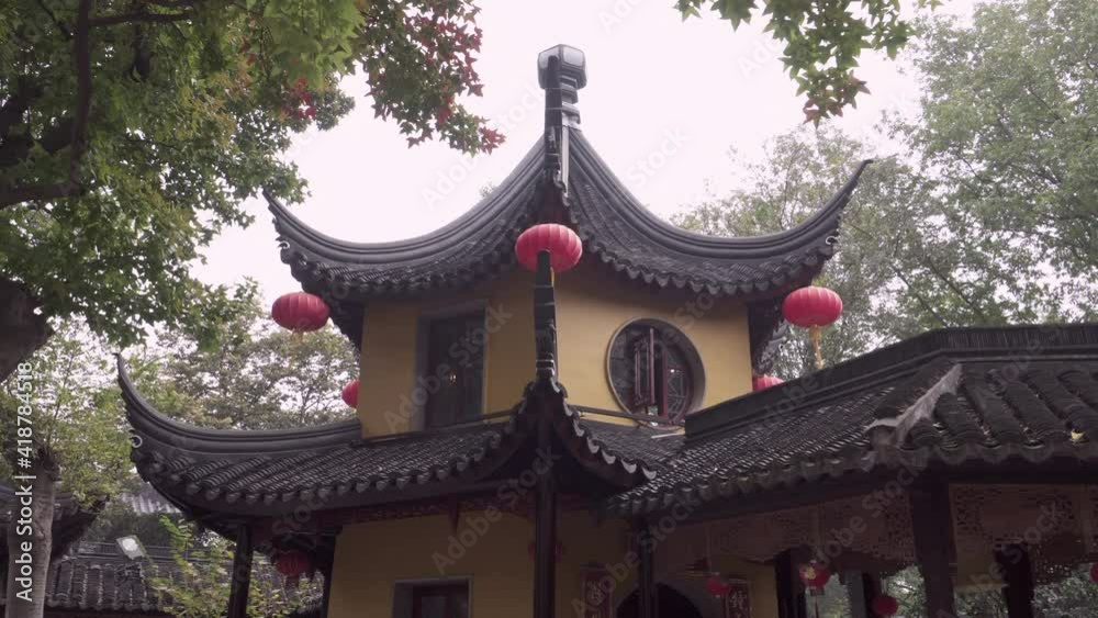 Panning shot of red lanterns hanging from Buddhist temple roof amidst trees - Suzhou, China Panning shot of red lanterns hanging from Buddhist temple roof amidst trees - Suzhou, China