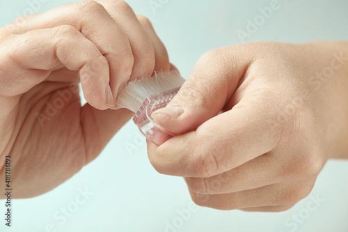 The girl sweeps away the dust with a manicure brush during cuticle treatment. The girl makes a manicure at home. Cuticle treatment on an isolated background. Close-up.
