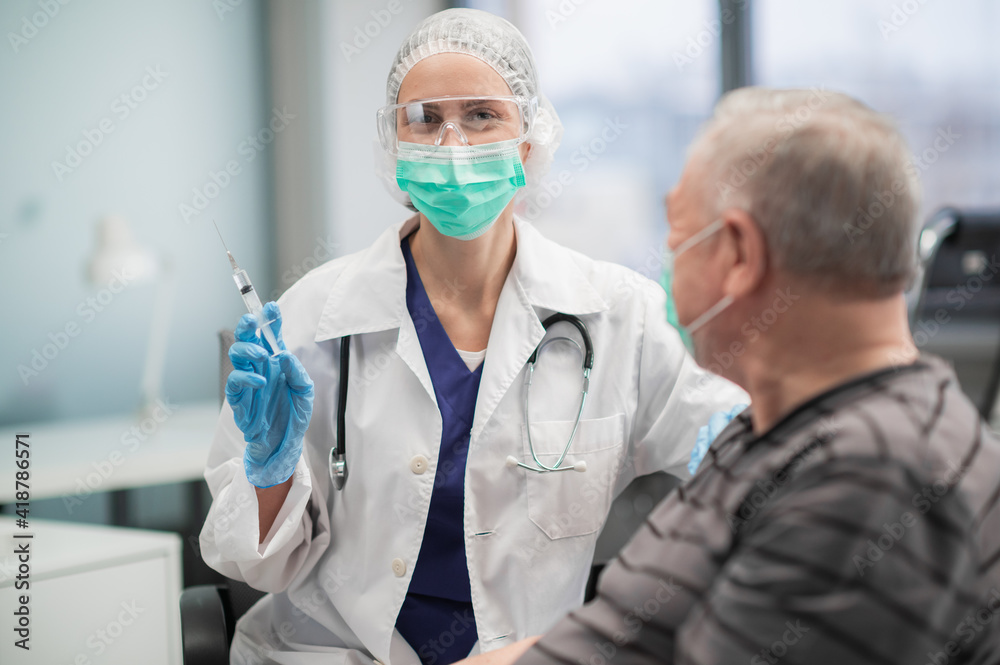 The program for vaccination of the population against the covid 19 virus strain. A nurse injects an injection into the arm of an adult male. The program for vaccination of the population against the covid 19 virus strain. A nurse injects an injection into the arm of an adult male.
