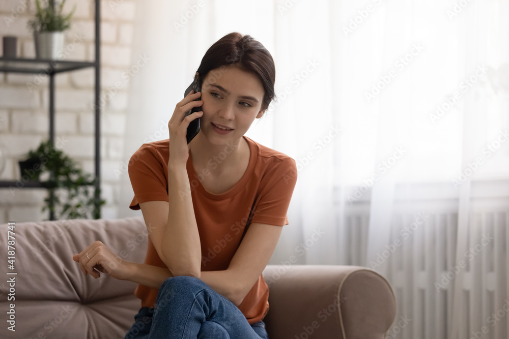 Phone conversation. Confident young woman sit on couch talk speak communicate by telephone from home holding device at ear. Teen female make answer call using cell listen to friend parent. Copy space Phone conversation. Confident young woman sit on couch talk speak communicate by telephone from home holding device at ear. Teen female make answer call using cell listen to friend parent. Copy space