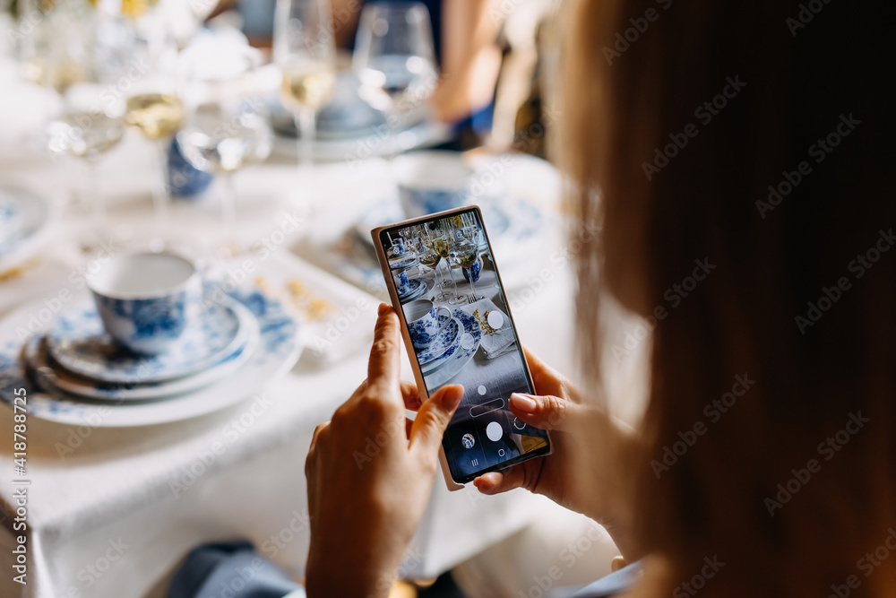 Woman taking photos of food on table with a smartphone.