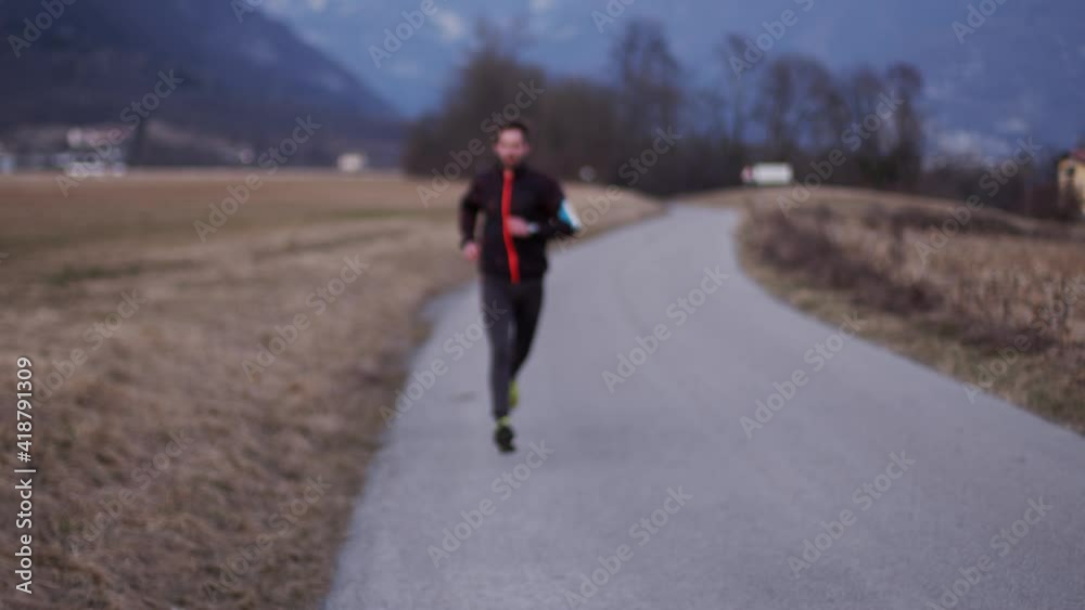 The athlete trains in the open air background of the street. The young man looks at the clock. The athlete trains in the open air background of the street. The young man looks at the clock.