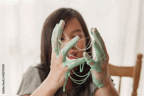 Hands with sticky gluey slime, mixed Asian girl making homemade slime toy, sensory art and craft, fun homeschool chemistry project