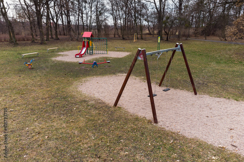 Lonely swing and slide at empty children playground.