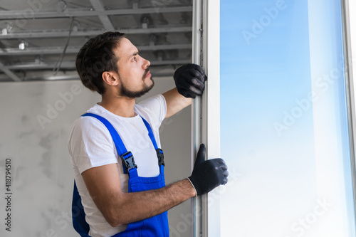 Bearded worker checks the plastic window in the apartment