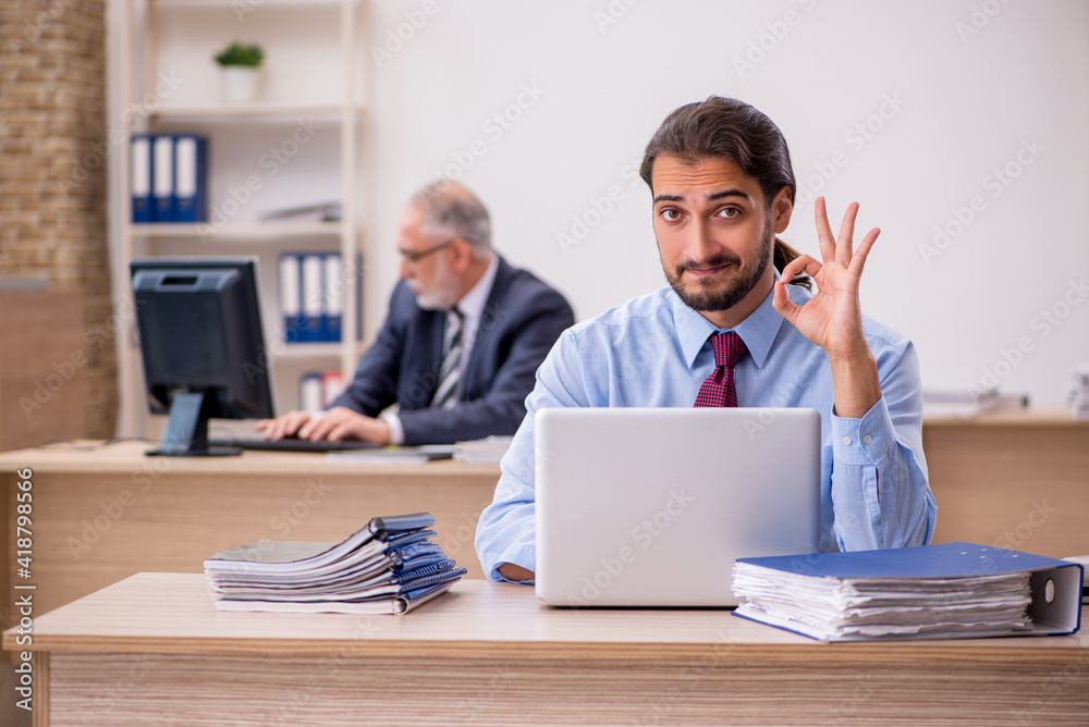 Old male boss and young employee working in the office Old male boss and young employee working in the office