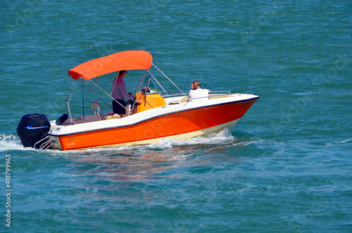 Small orange motor boat with white trim on Biscayne Bay off of Miami Beach,Florida.