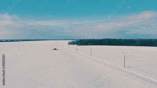 the electrical network is laid along the winter field. electric to remote settlements. wired electrical - Aerial Flight  © Dmytro