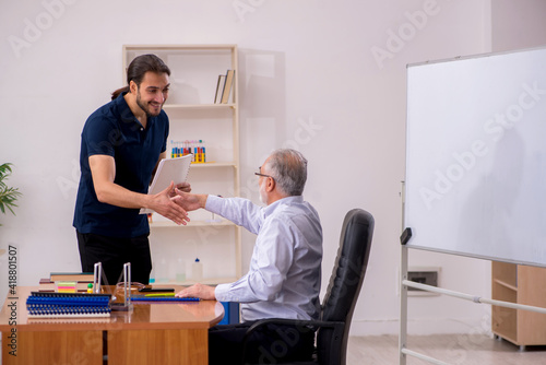 Old male teacher and young male student in the classroom