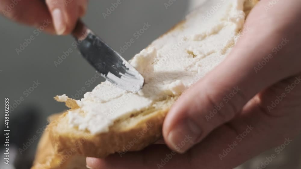 Close up hands girl or woman or chef prepares breakfast and spreads soft cheese or cream on crispy croissant. concept of delicious and hearty French breakfast in the morning.