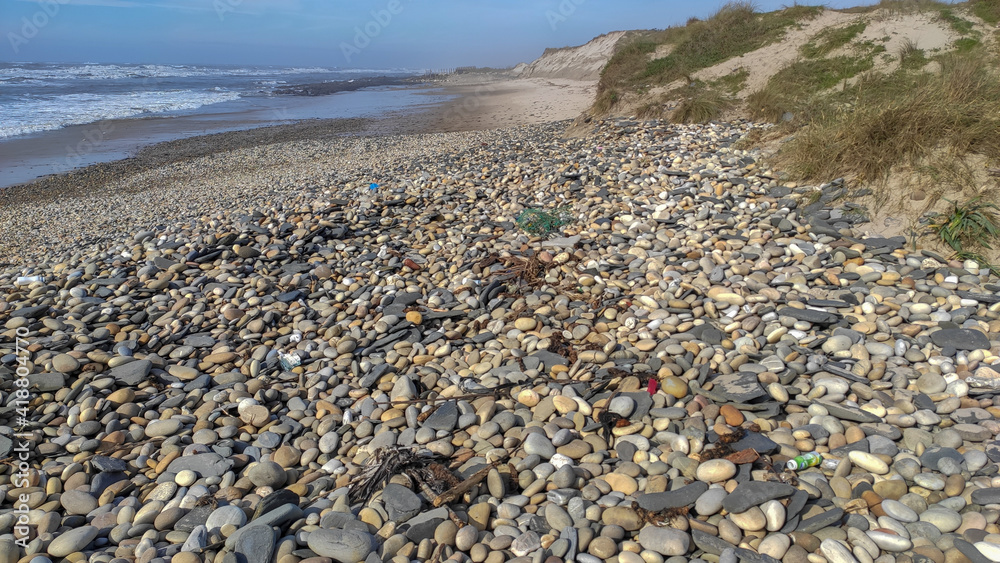Sea, beach boulders, pebble shore and waves. Sunny beach with sand dunes and blue sky in Esposende, Portugal. Polluted seashore. Polluted seashore. Plastic litter polluting the seashore. Sea, beach boulders, pebble shore and waves. Sunny beach with sand dunes and blue sky in Esposende, Portugal. Polluted seashore. Polluted seashore. Plastic litter polluting the seashore.