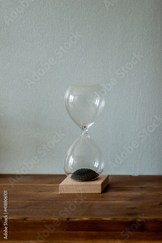 Minimalist hourglass on wooden surface on gray background. Magnetic hourglass.