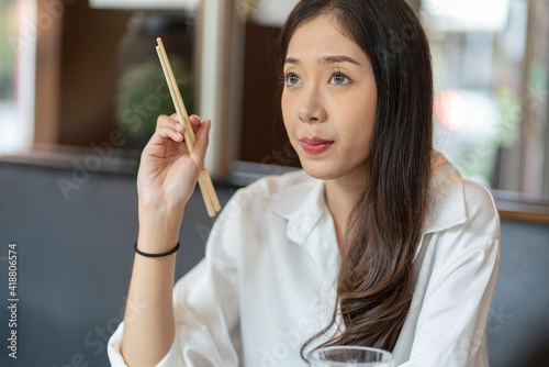 An Asian woman is a blogger, eats lunch and carries chopsticks, eats Chinese food at the Chinese food court. photo