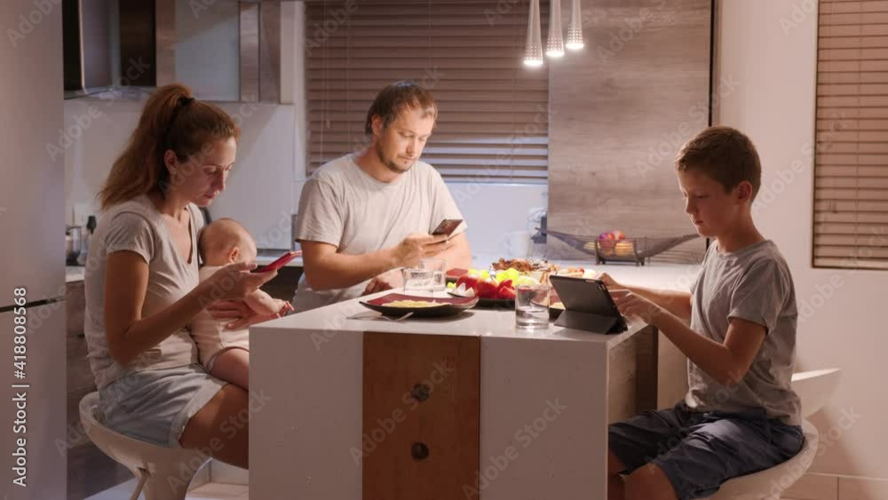 Family looking at smartphones during dinner at home. Family looking at smartphones during dinner at home.