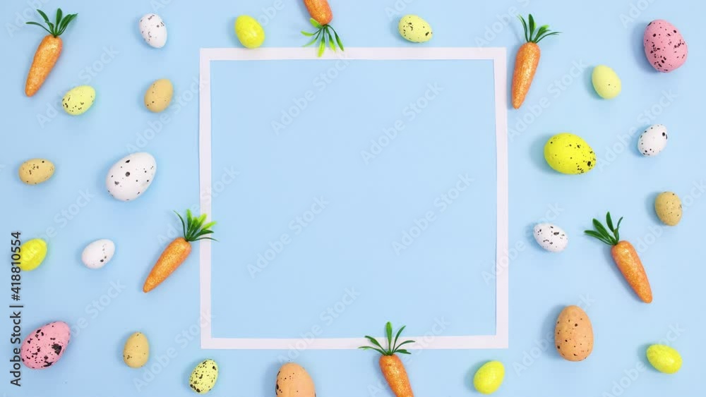 Easter vibrant eggs and carrots make creative pattern with copy space frame on bright blue background. Stop motion flat lay Easter vibrant eggs and carrots make creative pattern with copy space frame on bright blue background. Stop motion flat lay