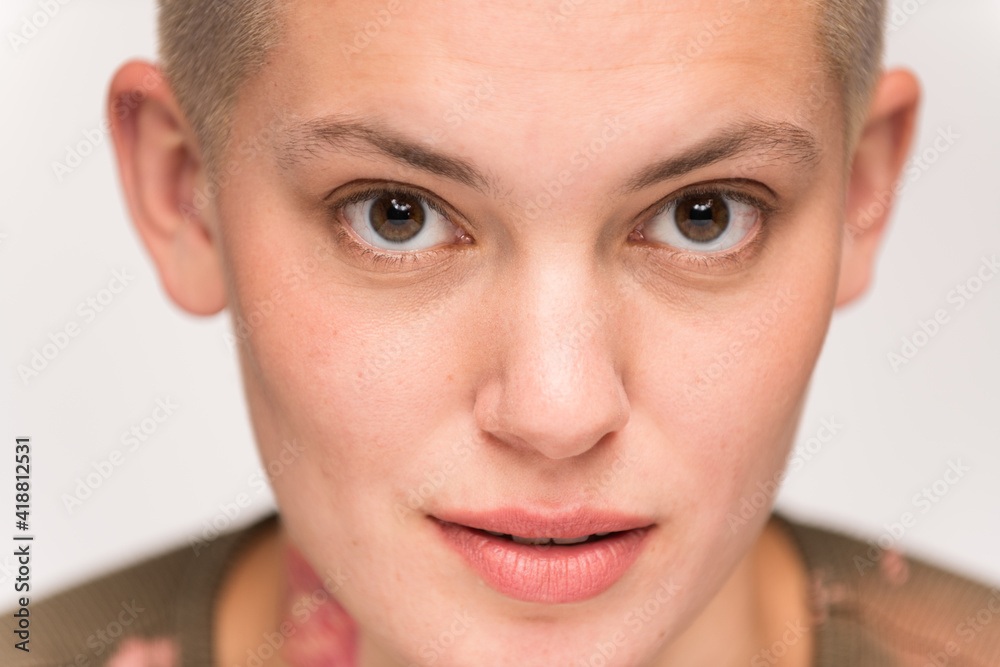Fototapeta premium Young urban woman with short blond hair poses before a light colored background.