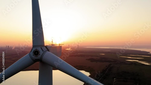 Massive wind turbine at sunset reverse drone reveal. over 400ft tall and still with rotor not moving. Sun flare as blade passes in front of sun. photo
