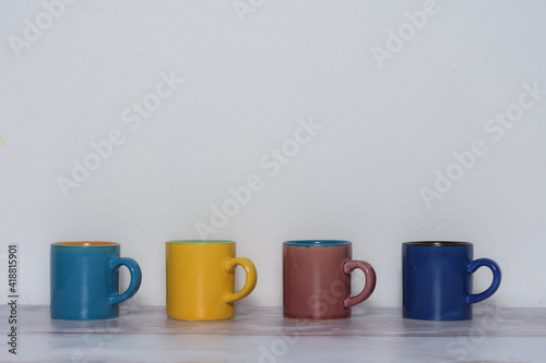 four cups of different colors arranged in a line available to write in them a four-letter word and also white space available above