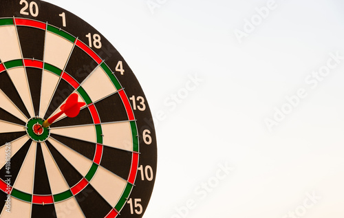 Dart arrow hit to center on bullseye(bull's-eye) of a dartboard is a target of purpose challenge business at sunset, expert strategy market target, objective financial and goal a concept