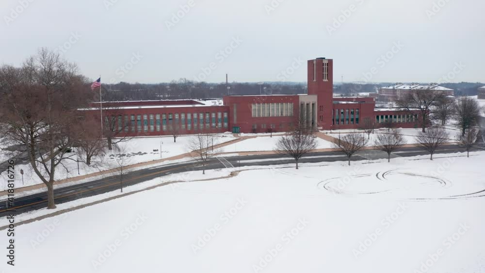 Wide aerial of school campus covered in white snow. America flag on flagpole. Cold winter scene. Wide aerial of school campus covered in white snow. America flag on flagpole. Cold winter scene.