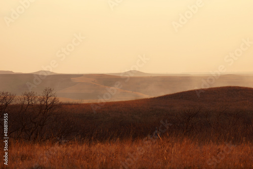 Prairie hills hazy with smoke during a wildfire on the open range. Peaks are visible in the distance.